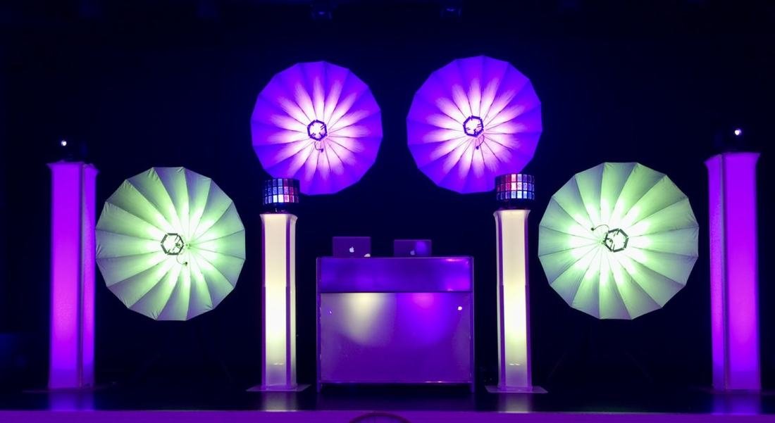DJ-Equipment mit großen Rund-Fächerleuchten in Grün und Lila, aufgebaut für eine Feier