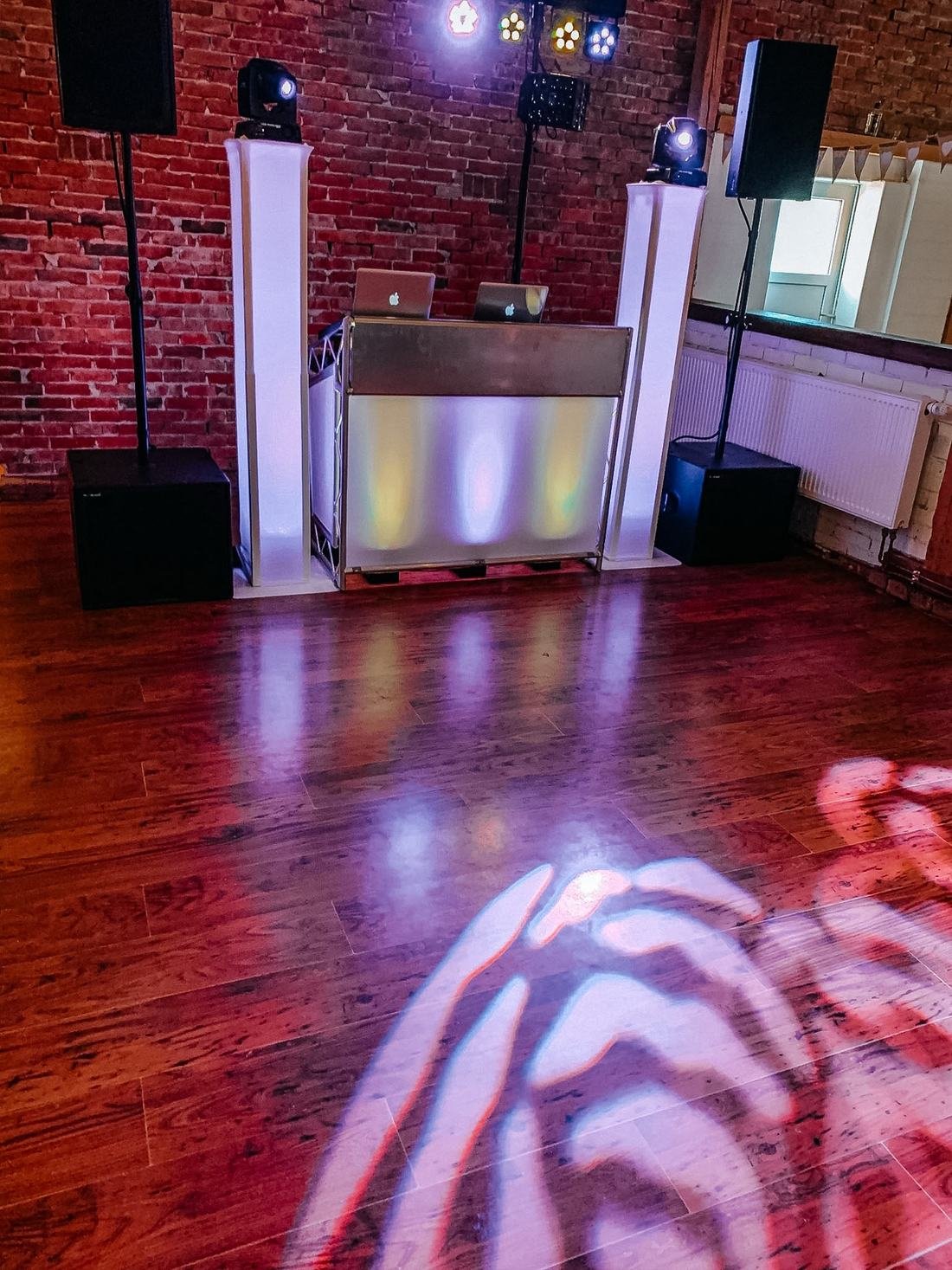 DJ-Equipment mit Lichtanlage in einem Loft mit Backsteinwänden, aufgebaut für ein Firmenevent